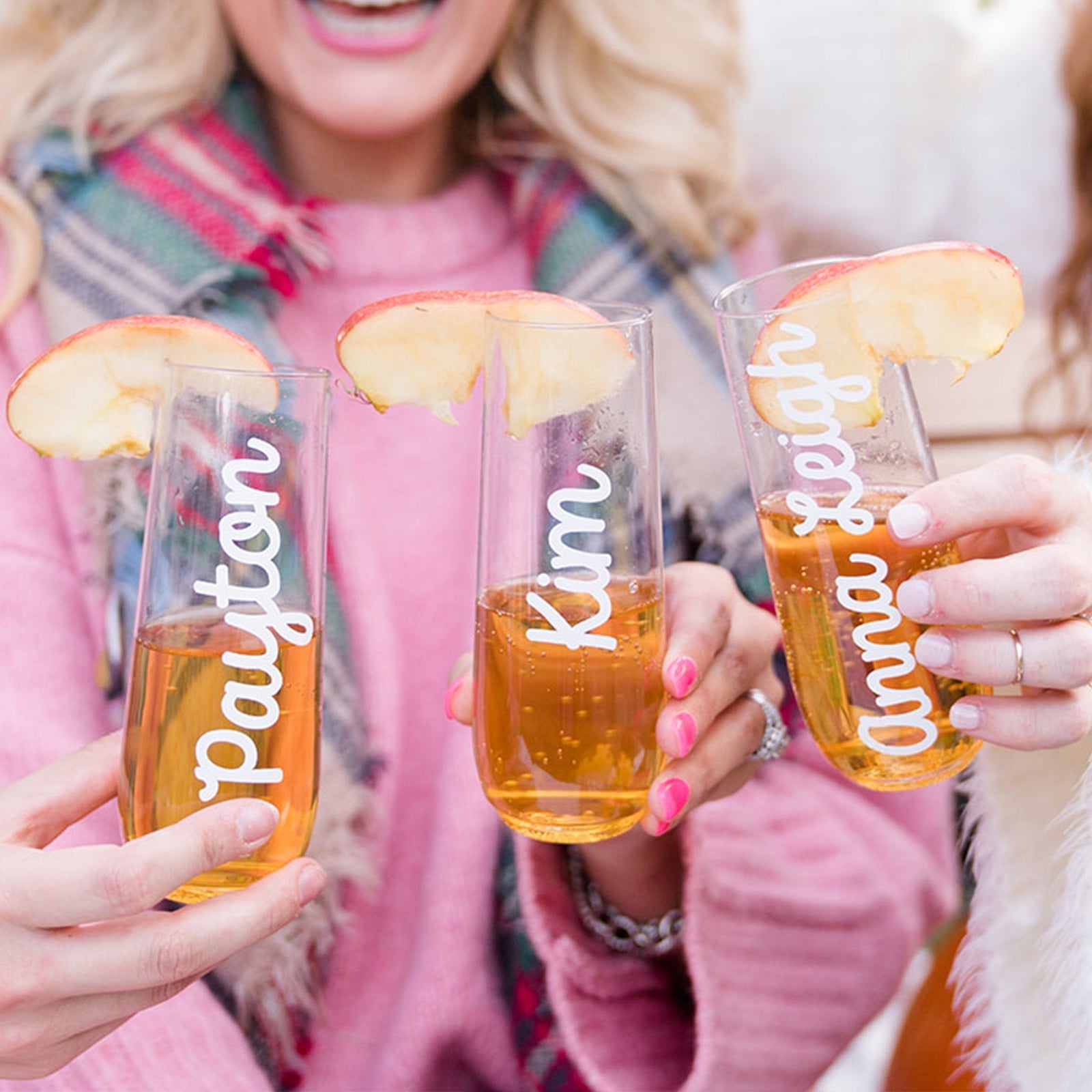 A champagne flute is customized with a name in a script gold font.