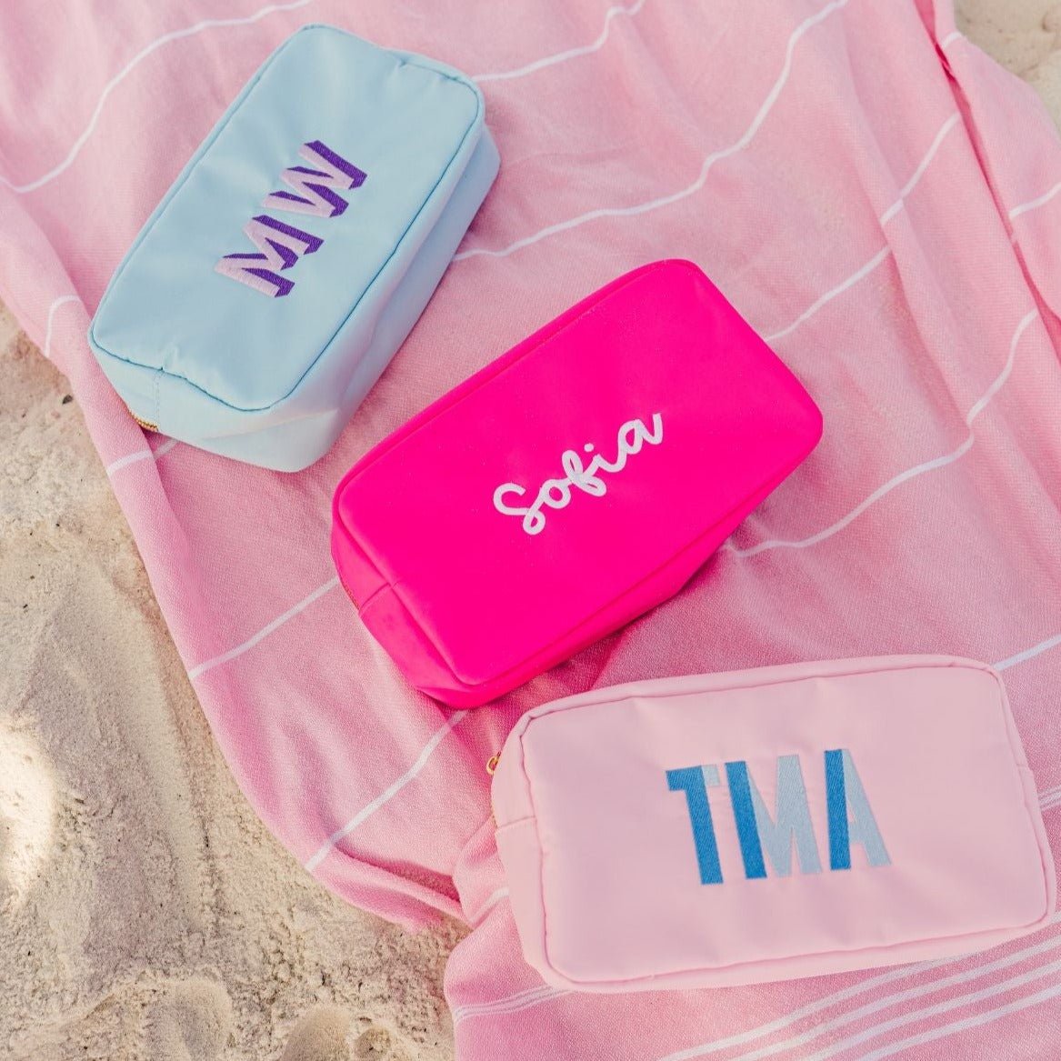Three extra large nylon pouches in blue, white, and pink