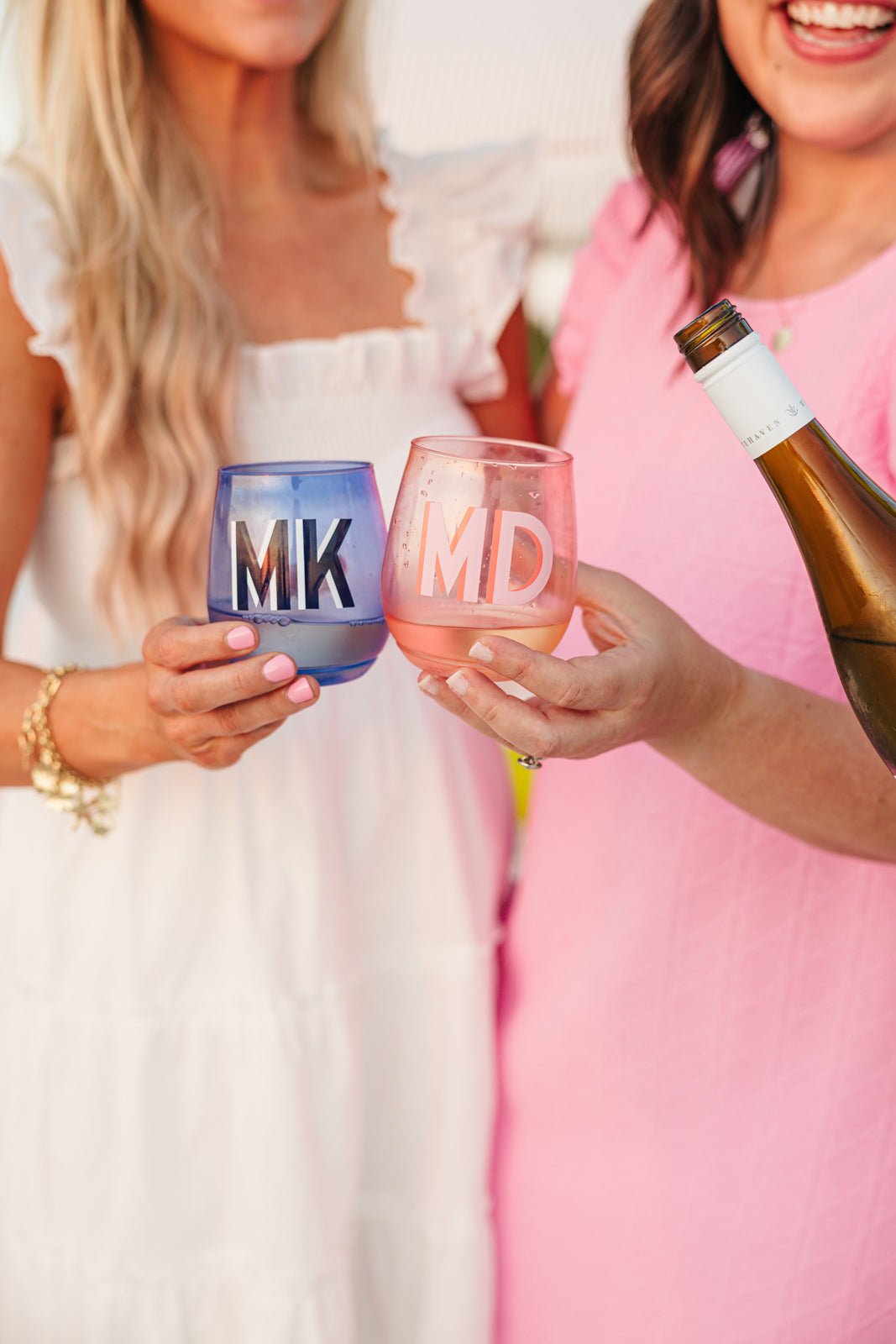 A pink, yellow, green, and a blue wine glass are personalized with different colored monograms.