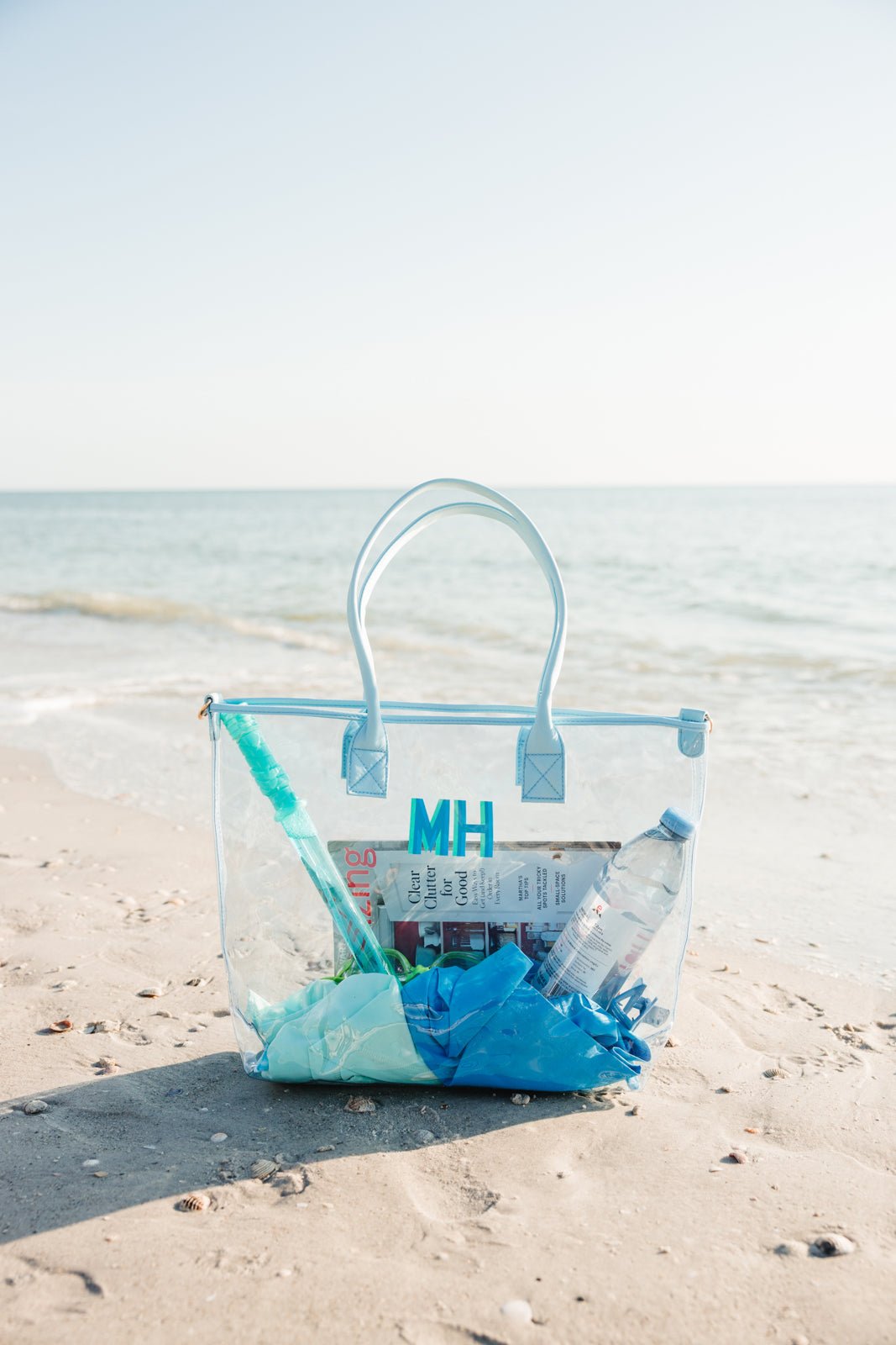 A white, pink, and a blue clear tote are personalized with different colored monograms.